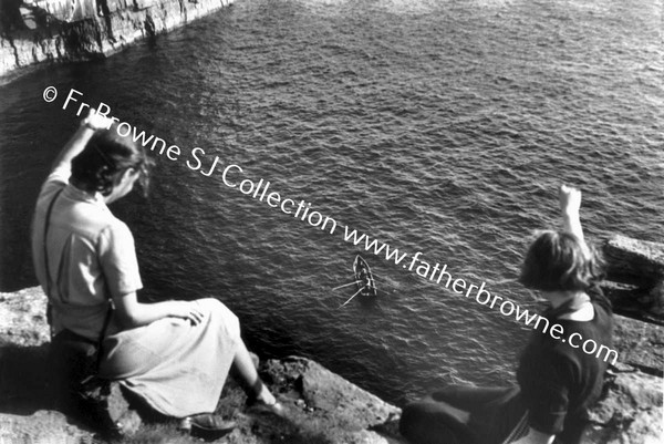 WOMEN SITING ON TOP OF CLIFFS LOOKING AT CURRAGH